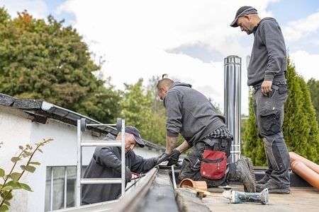 Drei Mitarbeiter stehen auf einem Dach und arbeiten